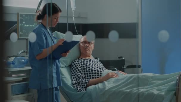 Enfermera caucásica revisando paciente anciano en sala de hospital - Metraje, vídeo