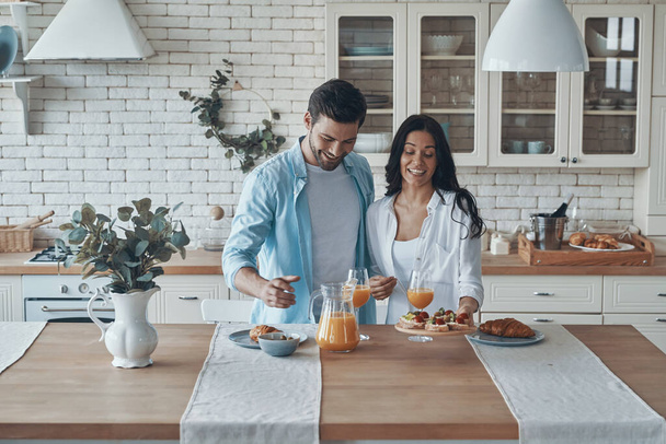 Boldog fiatal pár készít reggelit együtt, miközben időt tölt a hazai konyhában - Fotó, kép