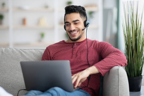 cara árabe feliz assistir webinar on-line, usando laptop e fone de ouvido - Foto, Imagem