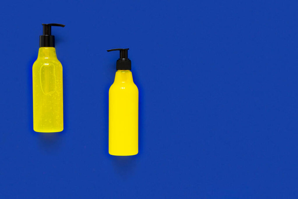 Bright cosmetic bottles on a blue background, top view. Packaging for branded products. Layout for a cosmetic kit. Flat lay - Фото, зображення