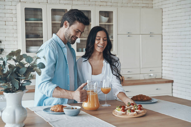 Carefree young couple preparing breakfast together while spending time in the domestic kitchen - Foto, Imagem