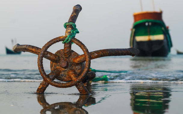 St. Martin 's Island, Bangladeş sahilinde demirli bir balıkçı teknesi. Balıkçı teknesi, deniz kıyısındaki bir sahilde geleneksel paslı bir çapa. Paslı çapa ıslak kumsal kumu ve el salla. - Fotoğraf, Görsel