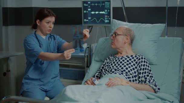 Νοσοκόμα που εξηγεί τα αποτελέσματα των ακτινογραφιών στον ασθενή στην νοσοκομειακή πτέρυγα - Πλάνα, βίντεο