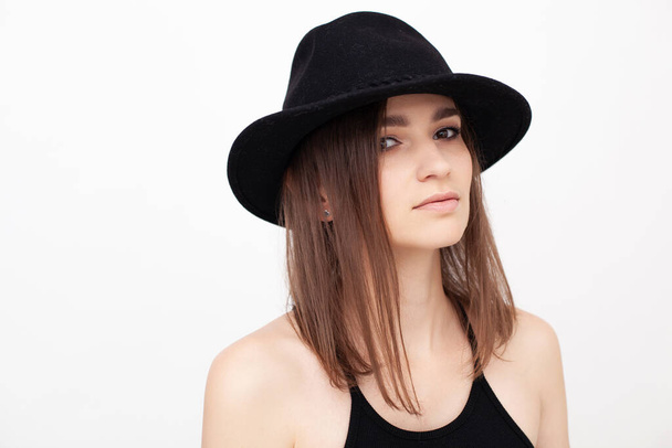 Portrait of a girl with beautiful eyes looking in the camera wearing black hat in the studio - Foto, Imagem