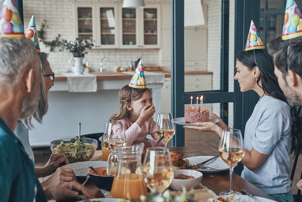 Happy family celebrating birthday of little girl while sitting at the dining table at home - Foto, Imagem