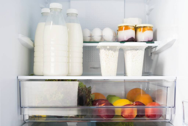 dairy products and fruits are on the shelf in refrigerators, close-up front view - Фото, зображення