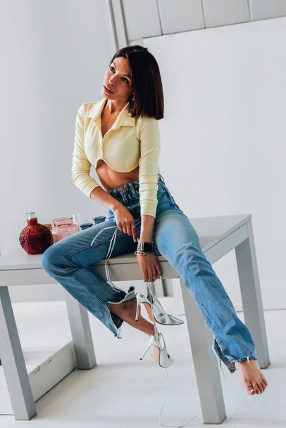 Stylist with a slim figure in jeans and silver sandals - Photo, Image