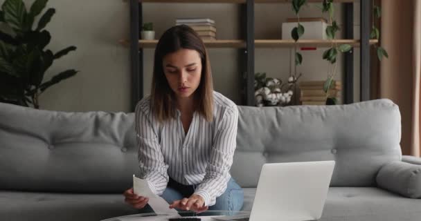 Concentrated young woman calculating household budget, making payments online. - Video