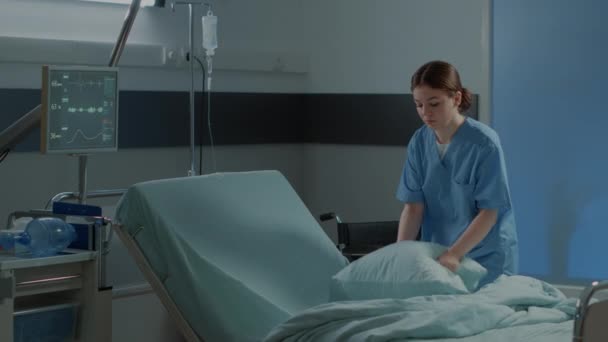 Enfermera caucásica haciendo cama de sala de hospital para su uso - Imágenes, Vídeo