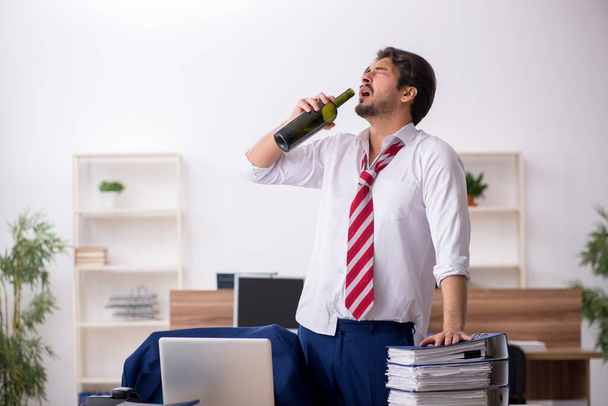 Fiatal alkoholfüggő férfi alkalmazott dolgozik az irodában - Fotó, kép