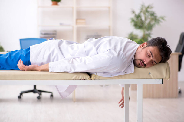 Stanco giovane medico maschio sdraiato sul divano in ospedale - Foto, immagini