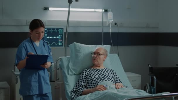 Medische verpleegkundige controleert patiënt op ziekenhuisafdeling in kliniek - Video