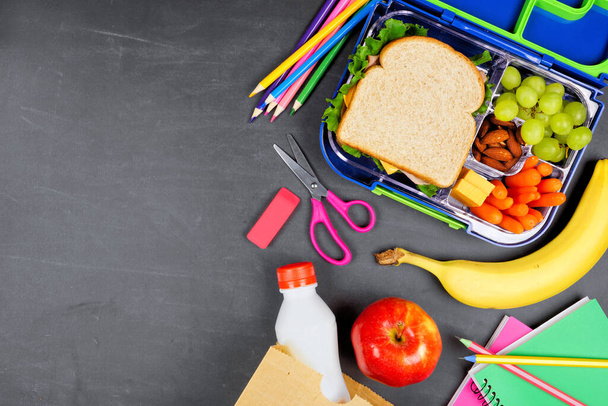 Sağlıklı okul beslenme çantası ve okul malzemeleri. Yan kenar, tebeşir tahtası arkaplanındaki üst görünüm. - Fotoğraf, Görsel