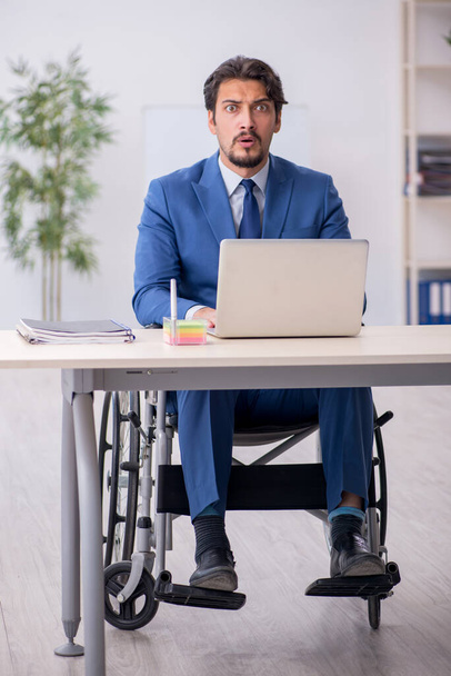 Jeune employé masculin en fauteuil roulant sur le lieu de travail - Photo, image