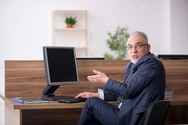 Aged male employee sitting at workplace - Foto, immagini