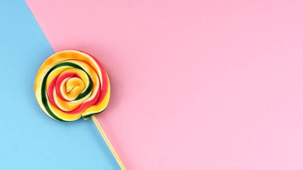 Flat lay of lollipop on pink and blue colored background minimalist concept - Photo, Image