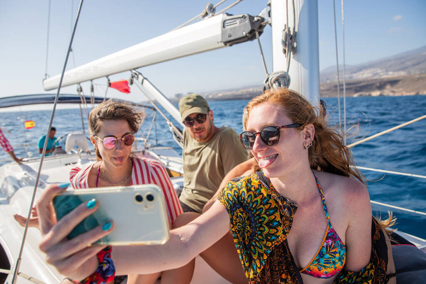 ryhmä ystäviä, kaksi naarasta ja yksi uros, ota selfie veneilyn aikana, onnelliset ihmiset kesäpäivän aikana nauttivat elämästä, yhdessä käsite. - Valokuva, kuva
