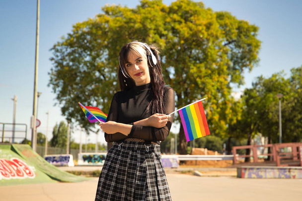 Linda chica joven con coletas, auriculares blancos y estilo punk con banderas de orgullo gay. - Foto, Imagen