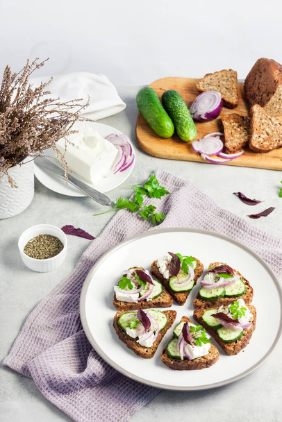 Canapés con pan tostado con semillas de girasol y lino, queso feta, pepino y cebolla - Foto, Imagen