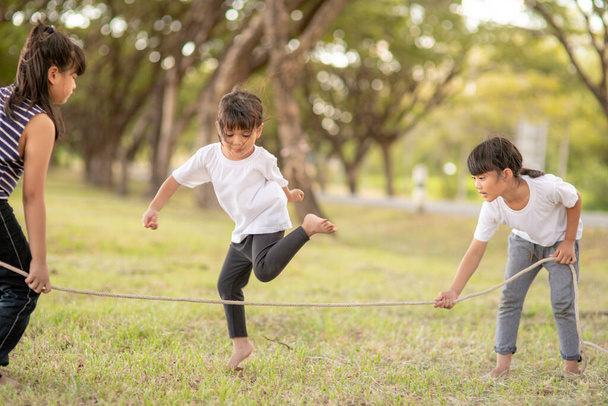 Happy kids playing together with jumping rope outdoors - Foto, Imagem