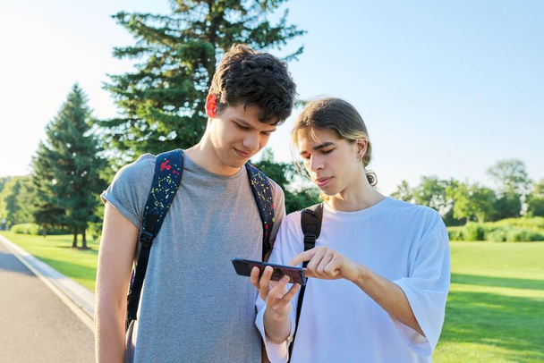 Teenagers friends talking looking at smartphone screen - Fotó, kép