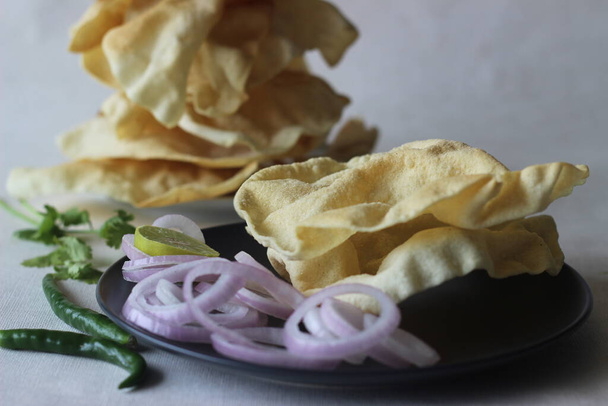Un papadum aussi appelé papade est un pain plat fin, croustillant et rond de l'Inde. Il est fabriqué par friture ou cuisson à chaleur sèche en le retournant sur une flamme nue. La pâte est faite de farine de gramme noir pelée. - Photo, image