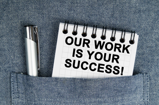 Concepto de negocios y finanzas. En mi bolsillo hay un bolígrafo y un cuaderno con la inscripción Nuestro trabajo es tu éxito - Foto, Imagen