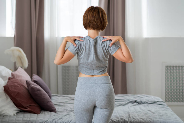 Young woman doing morning exercises in the bedroom, healthy lifestyle concept - Фото, зображення