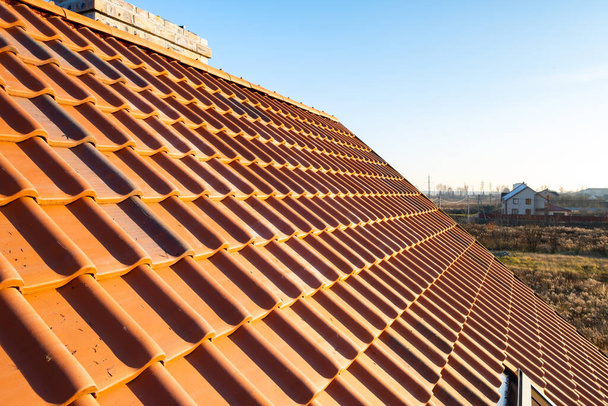 Overlappende rijen gele keramische dakpannen die het dak van een woongebouw bedekken. - Foto, afbeelding