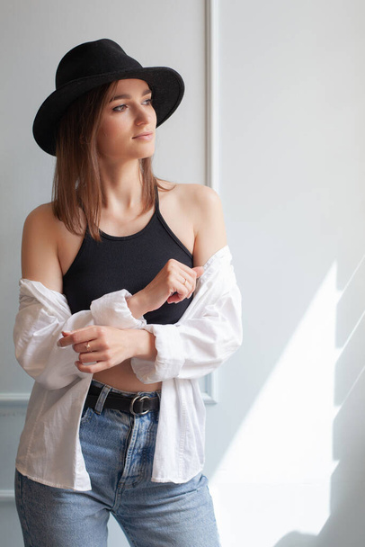 portrait of a young model woman in a hat on a white background in the studio in casual summer clothes catalog - Valokuva, kuva