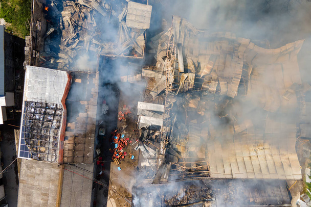 Widok z lotu płonącego budynku z zapadniętym dachem i rosnącym ciemnym dymem. - Zdjęcie, obraz