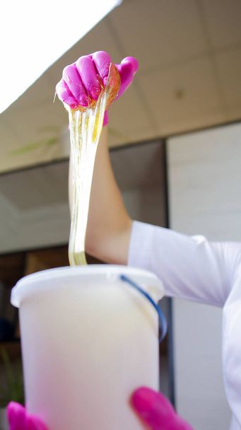 a pasta de açúcar flui abaixo das mãos do mestre da remoção de cabelo de açúcar - Foto, Imagem