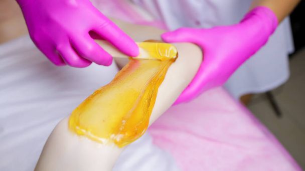 gros plan de l'application de la pâte à sucre sur la main du modèle, le maître applique la pâte avec une spatule spéciale - Photo, image
