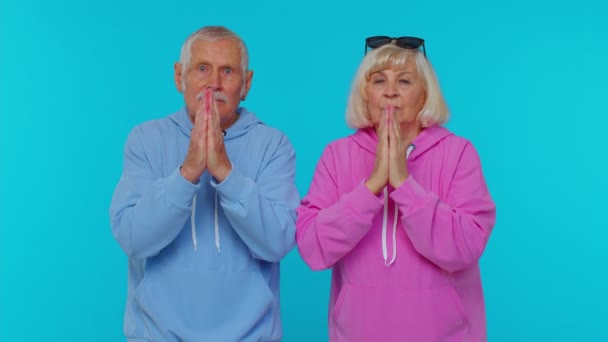 Senior grootvader grootmoeder bidden tot God, smeken excuses of hulp op blauwe studio achtergrond - Video