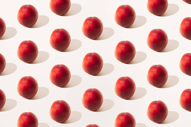 Aneinandergereihte rote Pfirsiche auf hellem Hintergrund. Minimales Sommermuster. - Foto, Bild