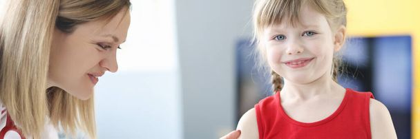 Pediatrician doctor inoculates little girl in shoulder - 写真・画像