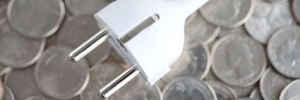 Електрична вилка, що лежить на купі монет крупним планом
 - Фото, зображення