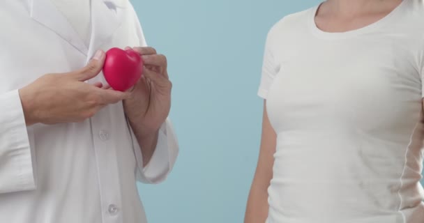 医師と色の背景に赤い心を持つ患者。心臓病の概念 - 映像、動画