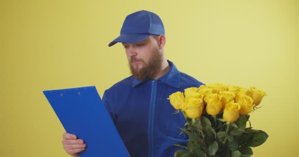 Kurier des Lieferdienstes übergibt Blumen an Kunden auf farbigem Hintergrund - Filmmaterial, Video