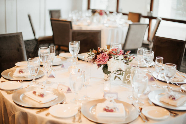 beautiful wedding venue with white table cloths, glassware, floral arrangements center pieces and fire place. - Photo, Image