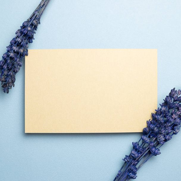 Almohadilla de memo beige con flores de lavanda púrpura sobre fondo azul. vista superior, espacio de copia - Foto, imagen