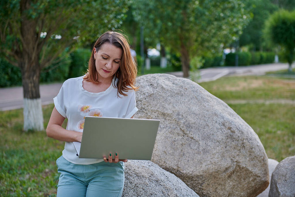 zajímavá dívka sedí na kameni s počítačem - Fotografie, Obrázek