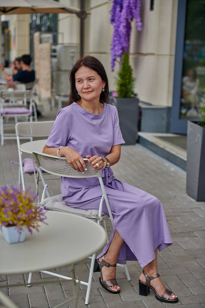 business woman in a lilac dress sits on a chair in a cafe asian - Foto, Imagen