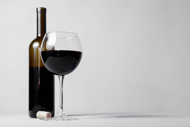 Red wine bottle without a label and glass filled iwth red wine. Over white background. Copy space banner. Wine concept. - 写真・画像