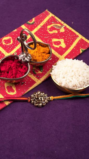 Festival indio: Raksha Bandhan fondo con un elegante Rakhi, granos de arroz y Kumkum. Una pulsera india tradicional que es un símbolo de amor entre hermanos y hermanas. - Foto, Imagen