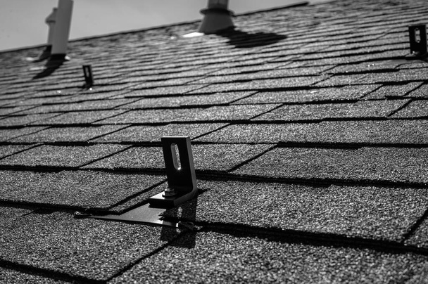 Residential asphalt shingle roof with metal anchors installed for the installation of a solar panel rail and racking system - Фото, изображение