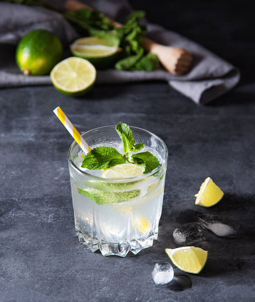 glass of lime lemonade mojito  with lime slices, ice  and  mint on dark background. Close up  image  - Photo, Image
