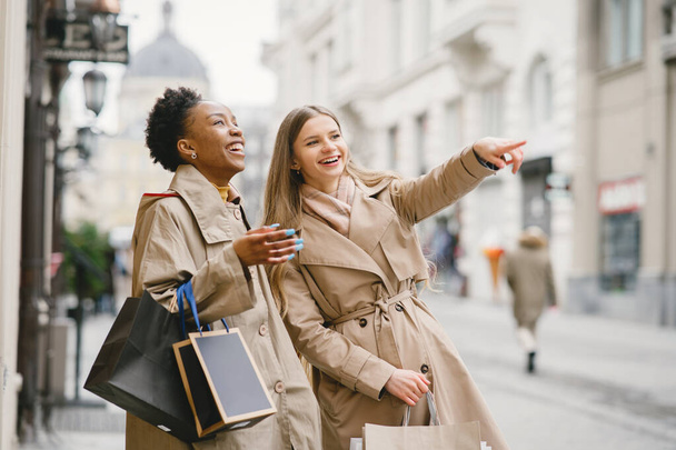 Szczęśliwe mieszane dziewczyny spacerujące ulicą z torbami na zakupy - Zdjęcie, obraz