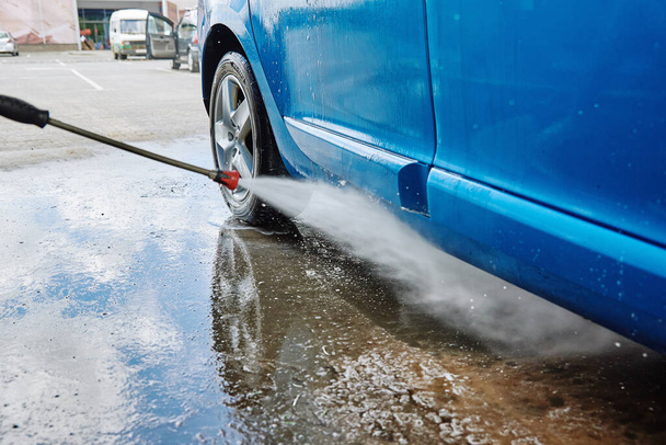 Nettoyage de voiture avec de l'eau haute pression à la station de lavage de voiture - Photo, image