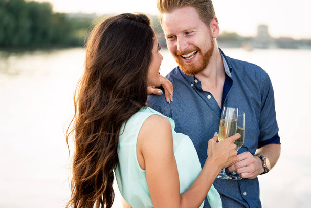 Summer holidays and dating concept. Happy beautiful romantic couple in love hugging with champagne - Foto, Imagem